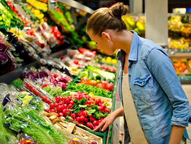 A young blond woman in the supermarket is looking for some fruits