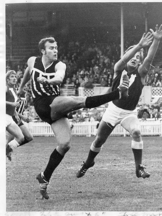 Footballer Peter Anderson trying to smother Eric Freeman's kick. SANFL football - Port Adelaide vs North Adelaide match Jul 1971.