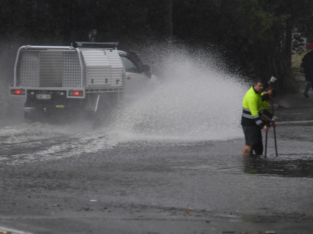 Council workers clear a drain as a car drives through floodwaters on Railway Terrace in Lewisham during wild weather in Sydney, Wednesday, November 28, 2018. Sydney received more than a month’s worth of rain in just two hours - with Observatory Hill recording 84.6mm by 7am. The November average is 83.8mm. Picture: AAP Image/Dean Lewins