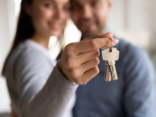 Close up happy woman hugging man, holding keys from new first house, young family celebrating moving day, satisfied customers couple purchase real estate, mortgage and relocation concept