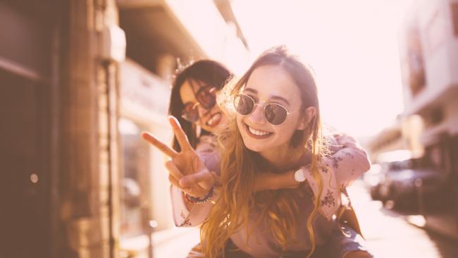 Hipster teenage girl on piggyback ride in the city doing the peace sign. Picture: iStock