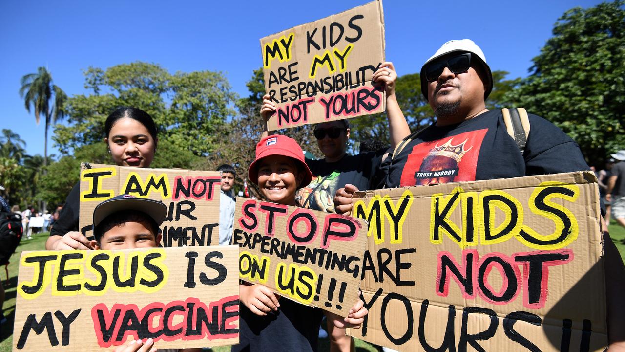 A family holds signs as people gather for a protest to rally against Covid vaccines and restrictions in Brisbane. Picture: NCA NewsWire / Dan Peled