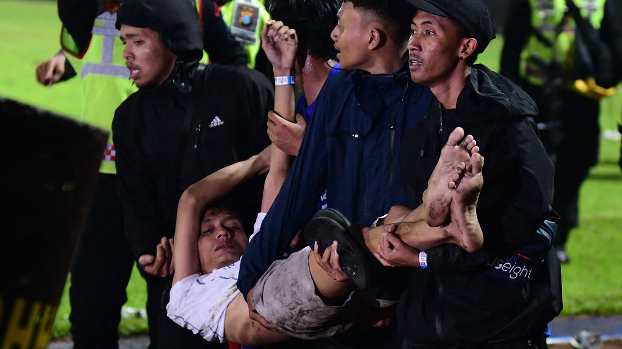 A group of people carry a man at Kanjuruhan stadium in Malang. Photo by AFP