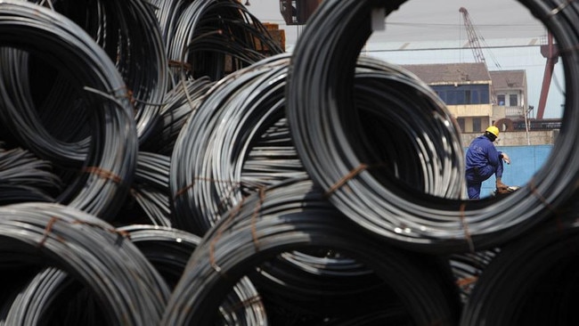 A worker is seen through stacks of steel wires at a steel stockyard in Shanghai, China.