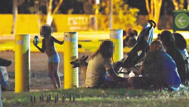 A family with young children sit beside the road near the BP service station in Tennant Creek after 10pm.