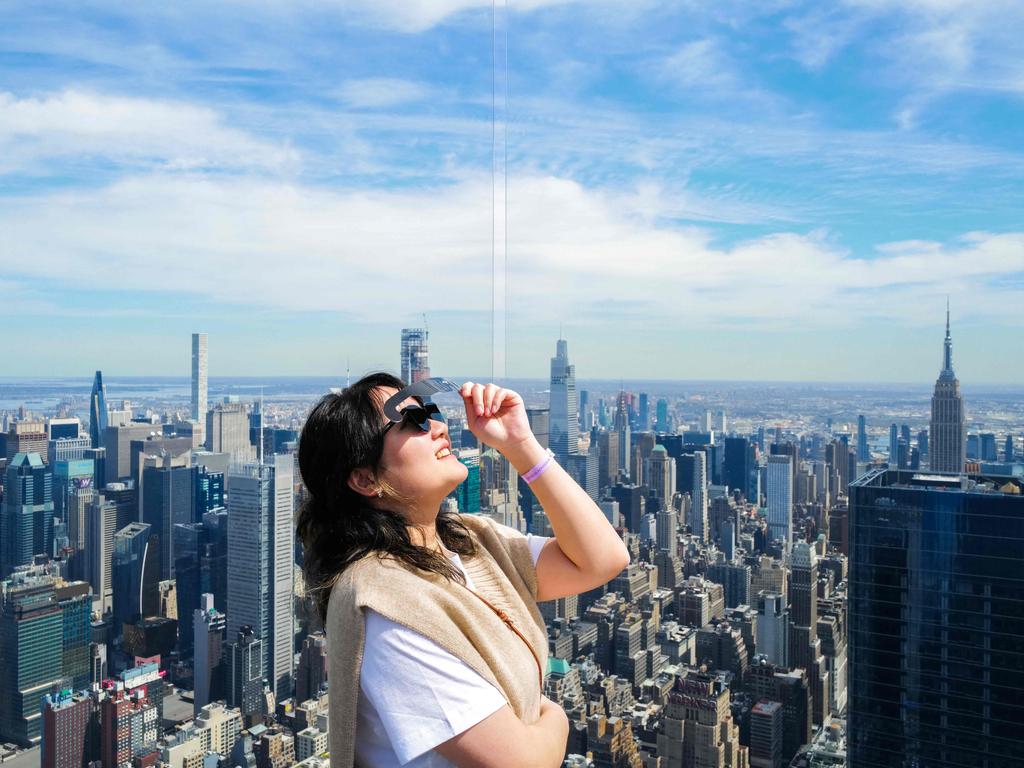 A woman looks toward the sky at an observation deck in New York City ahead of a total solar eclipse in the US, Mexico and Canada. Picture: AFP