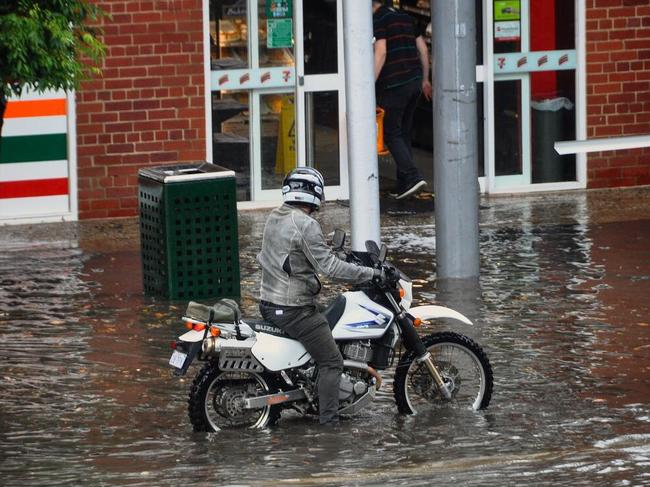 Undeterred, a motorcyclist rides through flooded Commercial Rd. Picture: Alexandra Owen