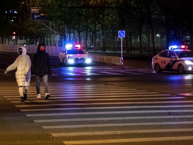 BEIJING, CHINA - NOVEMBER 29: Police cars drive through an intersection as they patrol in an area where there were rumours of a planned protest against the country's zero COVID measures on November 29, 2022 in Beijing, China. (Photo by Kevin Frayer/Getty Images)