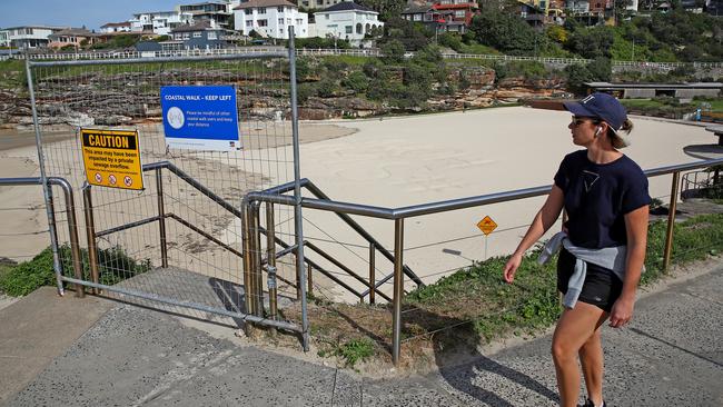 A woman walks past Tamarama beach, which is closed due to the social distancing rules now in place to help combat the coronavirus. Picture: Toby Zerna