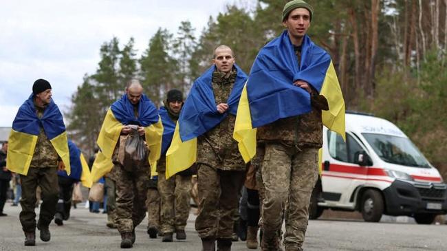 Some of the 175 Ukrainian prisoners of war wrapped with national flags, following an exchange with Russia at an undisclosed location. Picture: AFP.