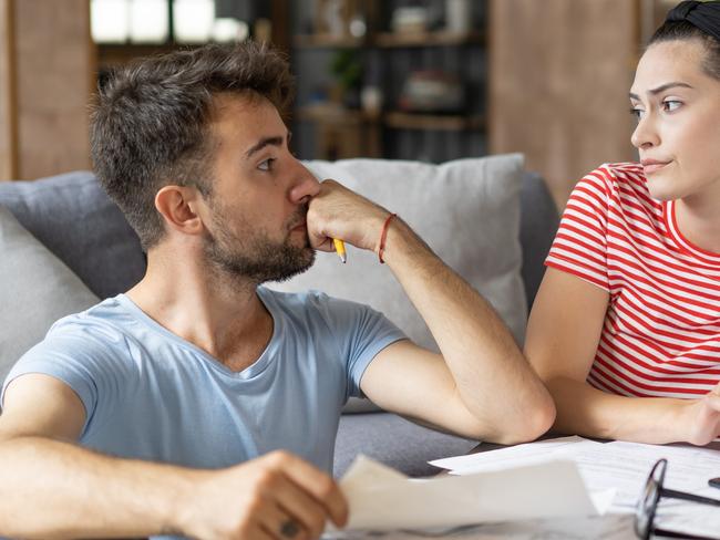 Frustrated concerned young couple calculating overspend budget, doing paperwork job at laptop, talking about financial problems, insurance, mortgage, fees, loan conditions, bankruptcy, economic inflation; money budgeting stress banking generic