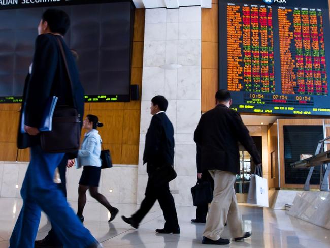 People walk in front of an electronic board which displays stock prices inside the Australia Securities Exchange (ASX Ltd.), building in Sydney, Australia, on Monday, Nov. 1, 2010. Singapore Exchange Ltd.'s A$8.1 billion ($8 billion) bid for ASX Ltd. will be vetted by Australia's Foreign Investment Review Board before approval, Prime Minister Julia Gillard said in an interview with the Australian Broadcasting Corp. Photographer: Ian Waldie/Bloomberg