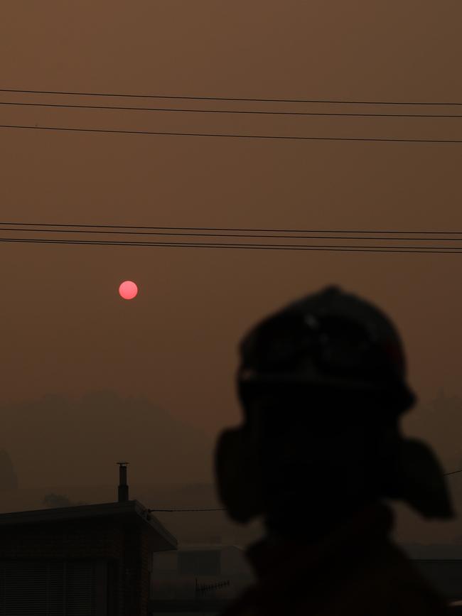 A firefighter at Geeveston Fire Station looking at the red sun as it goes down. Picture: LUKE BOWDEN