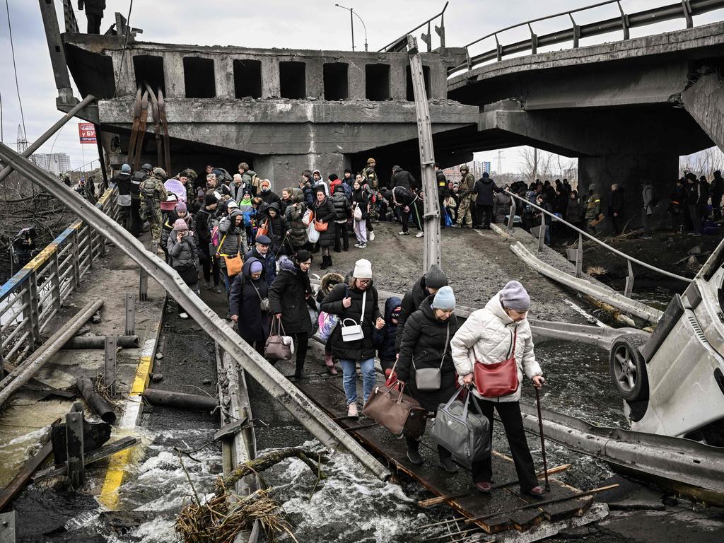 People cross under a bridge that was destroyed by a Russian air raid while fleeing the town of Irpin. Picture: Aris Messinis / AFP.