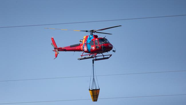 A chopper flys over head with a water bucket. Picture: Sarah Matray