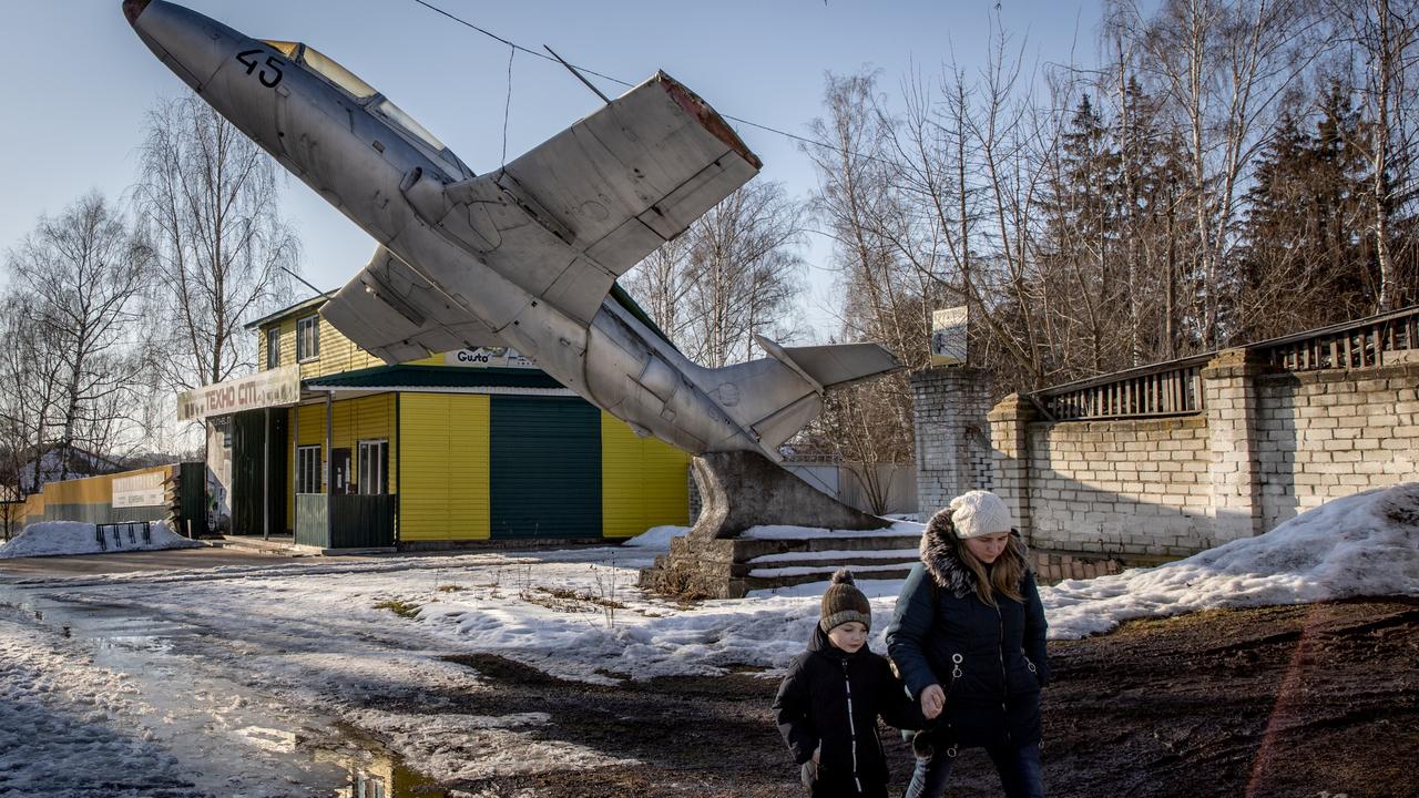 A woman walks underneath a military plane set as a monument to a former military base at a town on the outskirts of the Three Sisters border crossing between, Ukraine, Russia and Belarus in Senkivka, Ukraine. Picture: Chris McGrath/Getty Images