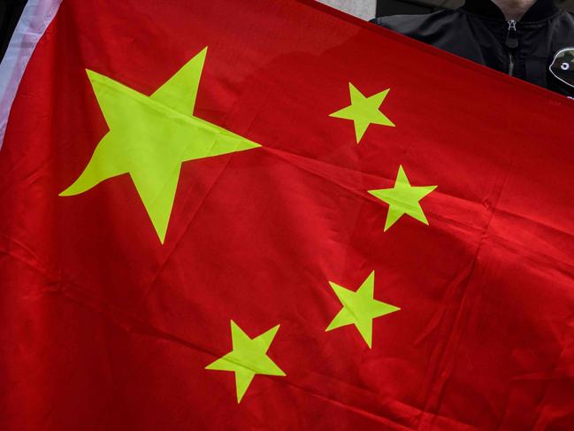 An man holds the national flag of China after a pro-Beijing activist group gathered outside the British Consulate-General to protest against the use of the British National (Overseas) passport in Hong Kong on February 1, 2021, as a new visa scheme offering millions of Hong Kongers a pathway to British citizenship went live the day before. (Photo by Anthony WALLACE / AFP)