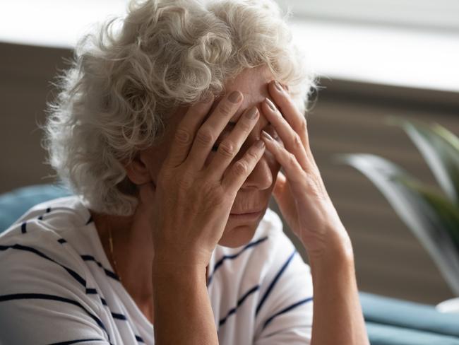 Close up 70s elderly woman sitting on sofa feels desperate crying covered face with hands, senile sickness need help, mental disorder or dementia, does not see way out difficult life situation concept  - Picture iStock