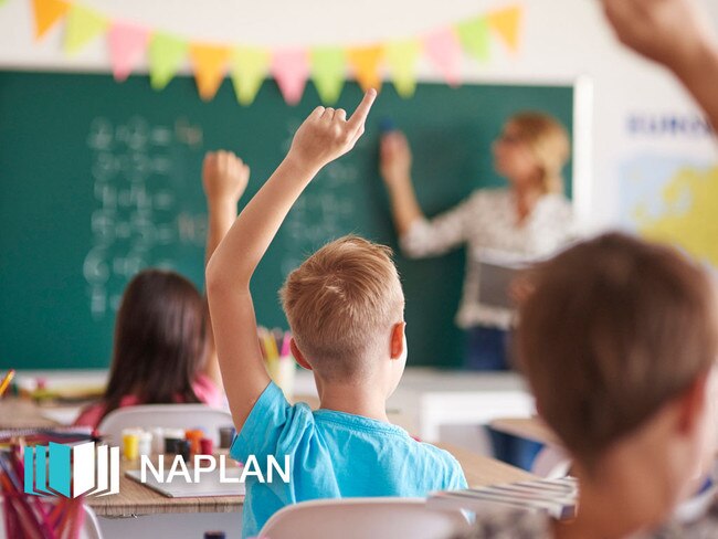 Children raising hands in class.