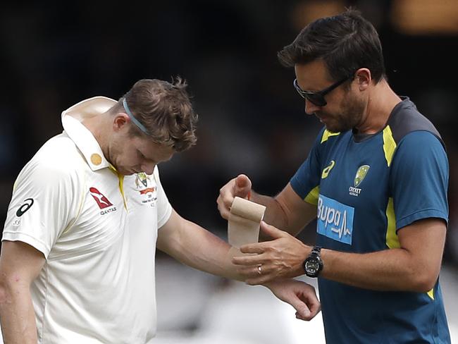 LONDON, ENGLAND - AUGUST 17: Steve Smith of Australia has his arm strapped by Australian Team Physiotherapist David Beakley after being struck in the arm by a delivery from Jofra Archer of England during day four of the 2nd Specsavers Ashes Test between England and Australia at Lord's Cricket Ground on August 17, 2019 in London, England. (Photo by Ryan Pierse/Getty Images)