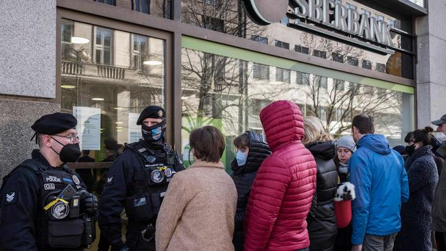 Police guard the entrance as people queue outside a branch of Russian state-owned bank Sberbank to withdraw their savings. Picture: AFP