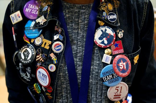 A woman shows off her button and pin collection during the Democratic National Committee 2023 Winter meeting