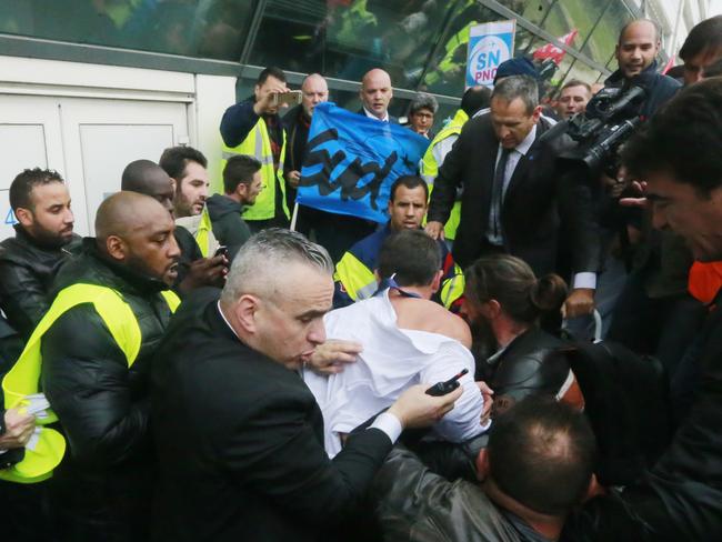 Violent turn ... Air France director of human resources Xavier Broseta (back to the camera) is protected by security guards as he flees the Air France headquarters at Roissy Airport. Picture: AP/Jacques Brinon