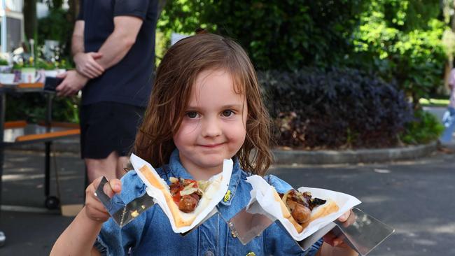 Indie, four, serves democracy sausages in Brisbane. Picture: NewsWire/Tertius Pickard