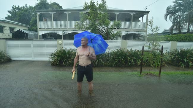 Pimlico resident John McGuire tries to get cars to slow down in the flooded road outside his home in Palmerston Street. Picture: Evan Morgan