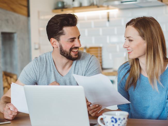 Young couple doing their finances at home. They are wearing pajamas and drinking first coffee of the day at the kitchen. Picture: Istock