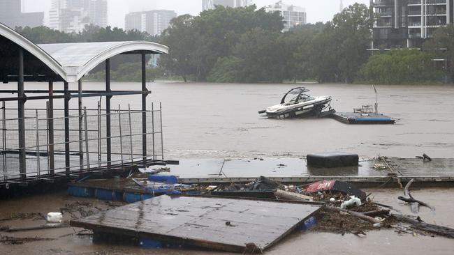 A boat and drifts past the old coating restaurant, in the Brisbane river, Flood waters rising in Milton on February 27. Picture: Steve Pohlner