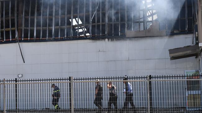 Investigators at the scene of the factory fire in Woolner on Thursday. Picture: KATRINA BRIDGEFORD