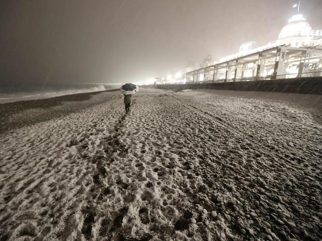 People walk through heavy snowfall on the beach along the Promenade des Anglais on February 28, 2018 in Nice. Picture: AFP