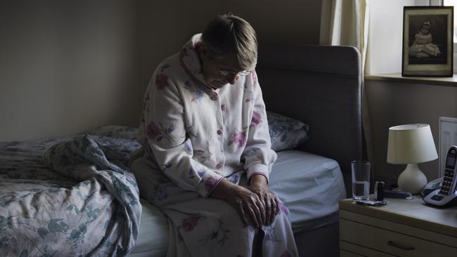 BAD AGED CARE:   A shot of a senior woman sitting on the side of her bed with her head down looking sad. She looks like she has just woken up as is dressed in nightwear.