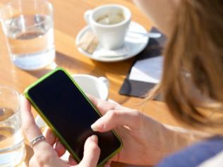 Close up portrait from behind of a young woman sending text message on mobile phone