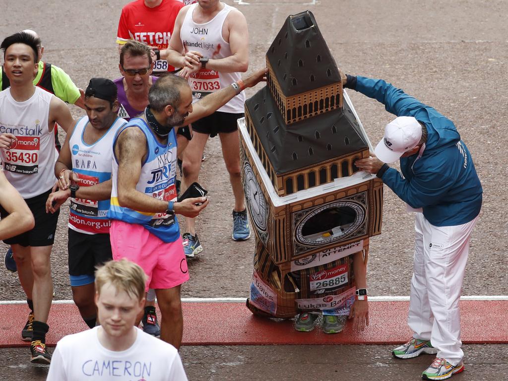 Lukas Bates wearing a costume of the Queen Elizabeth Tower (known as Big Ben) is helped by an official as he attempts to get past the finishing line, during the 39th London Marathon in London, Sunday, April 28, 2019. (AP Photo/Alastair Grant)