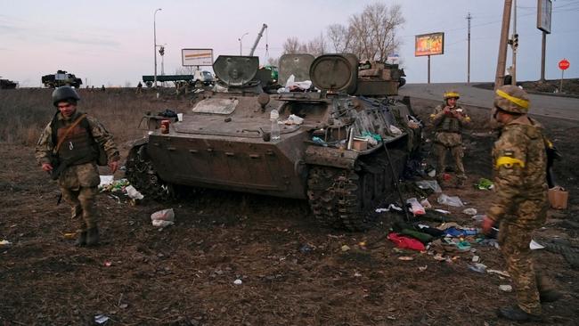 Ukrainian servicemen are seen next to a destroyed armoured vehicle, which they said belongs to the Russian army, outside Kharkiv, Ukraine February 24, 2022. REUTERS/Maksim Levin