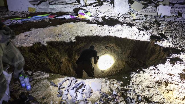 Members of Israel's Home Front Command and police forces inspect a crater left by an exploded projectile at a heavily-damaged school building in Israel's southern city of Gedera on October 1. Picture: Menahem Kahana/AFP