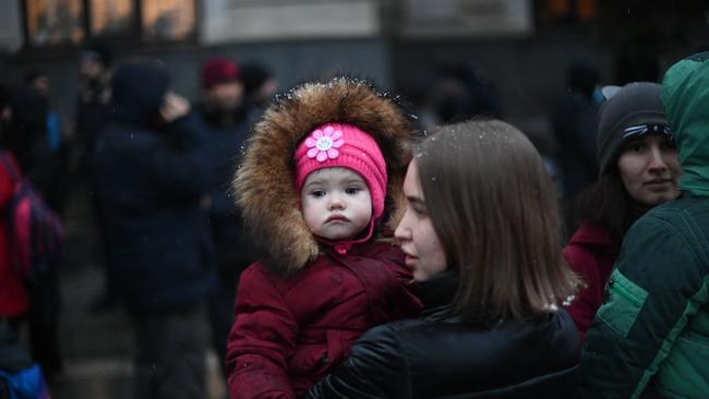 A young woman holds a child as they stand outside a train station in Lviv. Picture: Daniel Leal / AFP