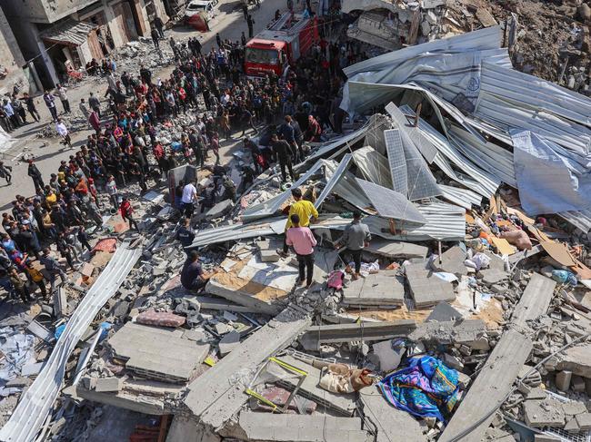 People gather around the rubble of a house destroyed in an Israeli strike as rescuers search for casualties on al-Jalaa street in central Gaza City. Picture: AFP