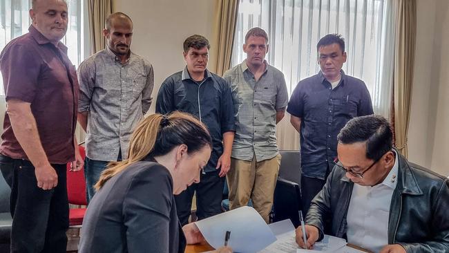 Left to right, back row: Martin Eric Stephens, Michael William Czugaj, Scott Anthony Rush, Matthew James Norman, and Si Yi Chen watch as Indonesian officials sign their transfer agreement in December 2024. Picture: AFP
