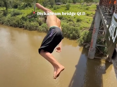 A still from the video of young men doing multiple somersaults  from the top of the arch of Queenslandâs oldest bridge at least 30m above the water has had almost 100,000 views and plenty of criticism.