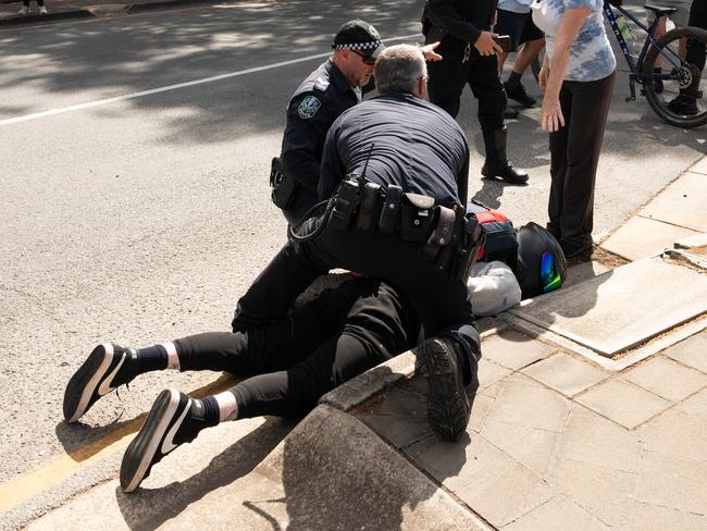 Police hold down a motorcyclist that collided with a cyclist at the SANTOS Tour Down Under in Tea Tree Gully on Thursday, January 18, 2023. (The Advertiser/ Morgan Sette)