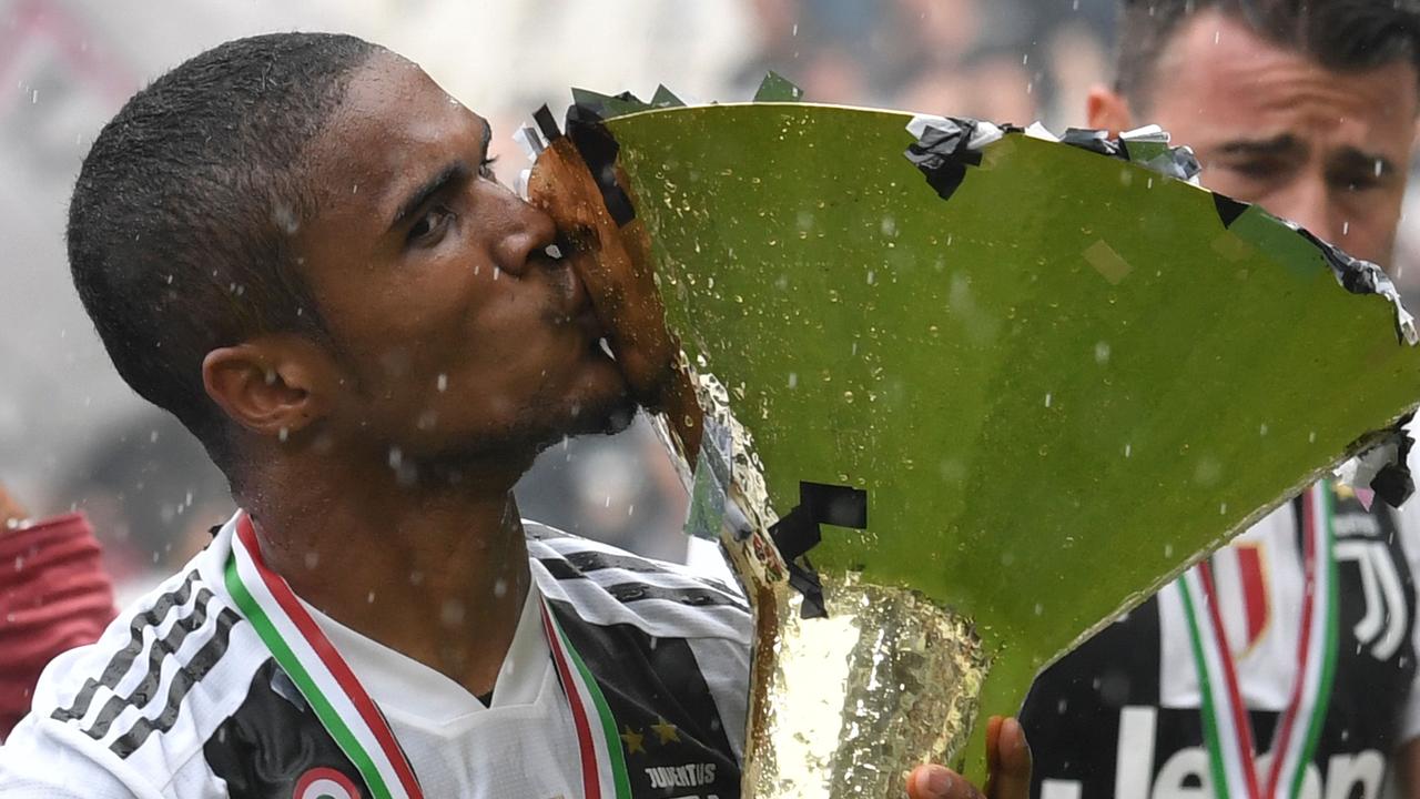 Juventus' forward from Brazil Douglas Costa kisses the trophy during the victory ceremony following the Italian Serie A last football match of the season Juventus versus Verona, on May 19, 2018 at the Allianz Stadium in Turin. Juventus won their 34th Serie A title (scudetto) and seventh in succession. Italy great Gianluigi Buffon played his last game with Juventus today after 17-year with the Serie A champions. / AFP PHOTO / Andreas SOLARO