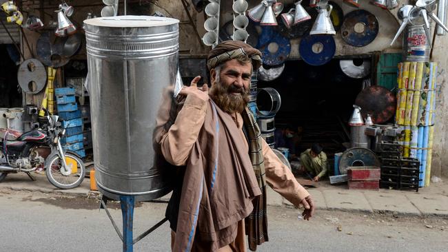 A man carries a water canister as he walks past a blacksmith shop in Kandahar. Picture: AFP