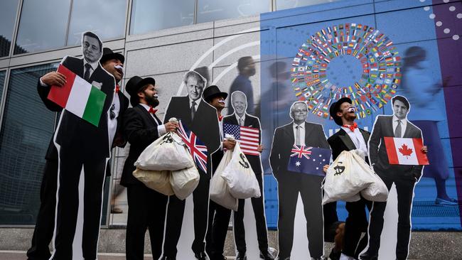 TOPSHOT - Activists dressed as debt collectors hold cutouts of the leaders of Italy, Mario Draghi, United Kingdom, Boris Johnson, United States, Joe Biden, Australia, Scott Morrison and Canada, Justin Trudeau during a demonstration in front of the International Monetary Fund headquarters to ask rich nations to keep their comitment to support developing countries to tackle climate change in Washinton DC on October 13, 2021.. (Photo by Pedro UGARTE / AFP)