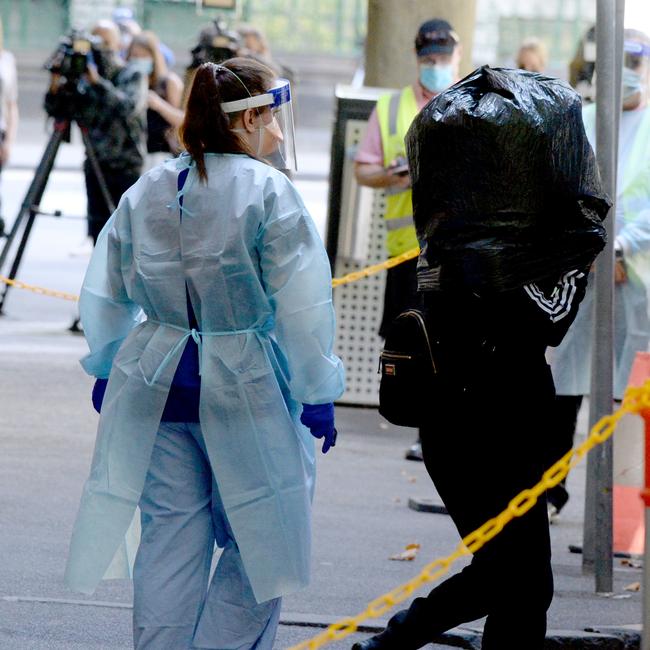 A quarantined coronavirus positive international traveller boards a coach outside the Holiday Inn on Flinders Lane to be transported to the Pullman Albert Park. Picture: NCA NewsWire / Andrew Henshaw