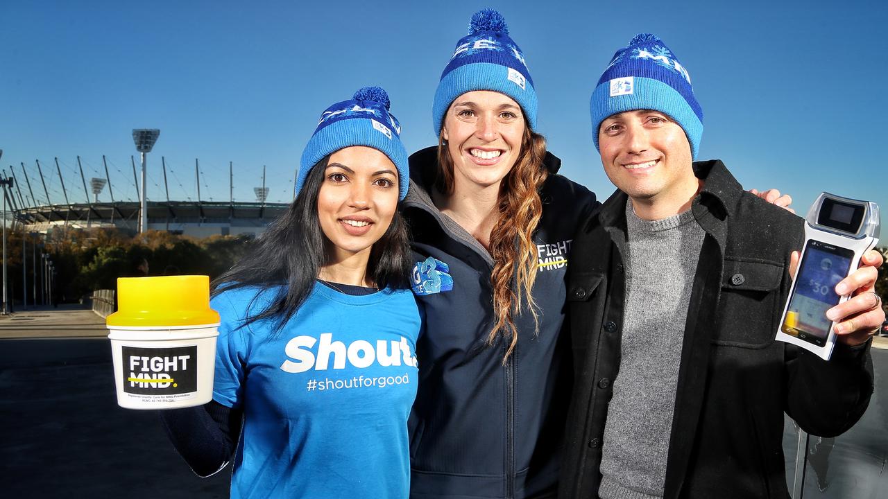 Bec Daniher (centre) with volunteers Andrea White and Charlie Carpinteri are ready for Fight MND donations with a traditional donation tin and a BladePay mobile payment device outside the MCG in 2017. Picture: Hamish Blair