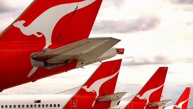 Qantas aircraft tails at Kingsford Smith Airport in Sydney as baggage handlers deliver luggage. plane airline logo tail/Qantas/Airways/Ltd