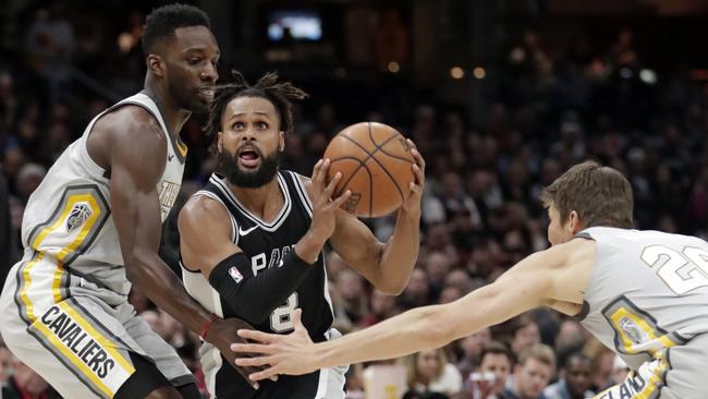 San Antonio‘s Patty Mills drives between Cleveland Cavaliers' Jeff Green, left, and Kyle Korver